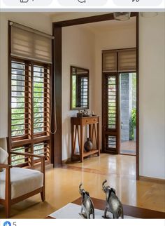 an open living room with wooden shutters on the doors and two elephant statues in front of them