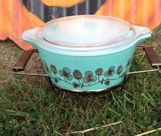 a blue casserole dish with flowers painted on it sitting in the grass next to a skateboard