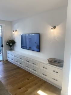 a flat screen tv mounted to the side of a wall next to a wooden floor