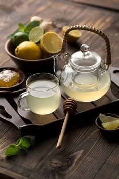 a glass tea pot filled with lemonade next to two cups