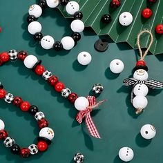 a christmas tree made out of ornaments and beads on a table with a snowman ornament