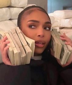 a woman holding stacks of cash in front of her face and looking at the camera