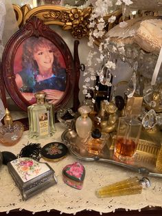 a table topped with lots of different types of perfumes and other decorative items next to a mirror