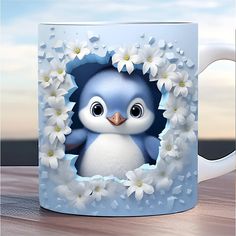 a blue and white mug with a little penguin in it's center surrounded by flowers