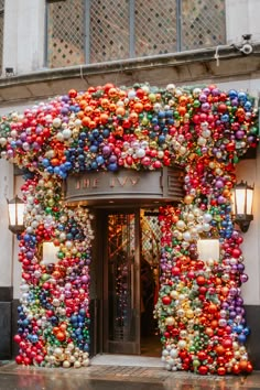 an entrance to a building decorated with christmas balls and ornaments on the outside, in front of a street light