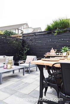 an outdoor seating area with benches and tables in front of a fenced in backyard