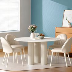 a white table and four chairs in a room with blue walls, hardwood floors and wooden furniture