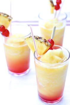 three glasses filled with drinks and topped with pineapples