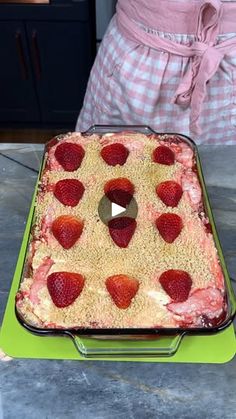 a cake with strawberries on it sitting on top of a green tray next to a pink towel