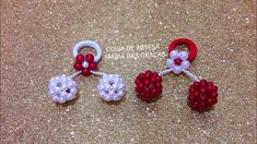 three red and white beads are attached to the handles of some earrings on a glittery surface