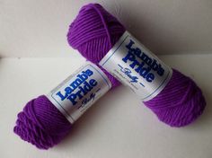 two skeins of purple yarn sitting next to each other on a white surface