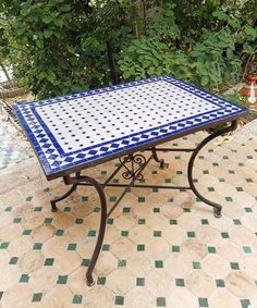 a blue and white table sitting on top of a tiled floor next to a tree