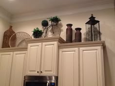 the kitchen cabinets are all white and have vases on top of them, as well as an oven