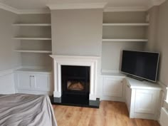 an empty bedroom with a fireplace and built - in shelving