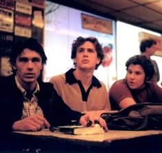 three young men sitting at a table in a restaurant looking up to their left side