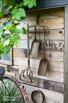 an old garden tool rack with gardening utensils hanging from it