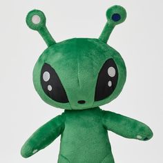 a green alien stuffed animal with big eyes and nose piercings on it's head