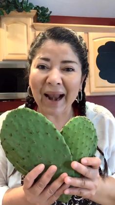 a woman holding two green cactus halves in front of her face and making a funny face