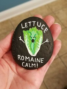 a hand holding a rock that says lettuce romaine calm