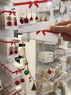 a person is holding up some christmas themed jewelry in front of the store's display