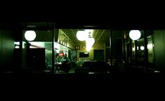 two people standing in the doorway of a building at night with three lights on them