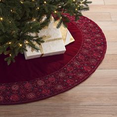 a christmas tree with presents under it on a red rug