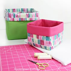 sewing supplies are sitting on top of a pink cutting board with scissors and tape next to it