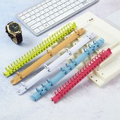 four different colored combs sitting next to a keyboard and watch on a table top