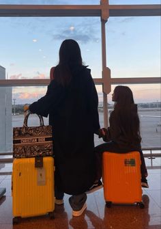 two people with luggage looking out an airport window