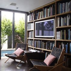 two chairs in front of a bookshelf with a television on top of it