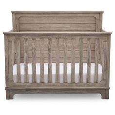 a wooden crib with white sheets on the bottom and side rails, against a white background