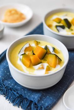 two white bowls filled with soup on top of a blue napkin