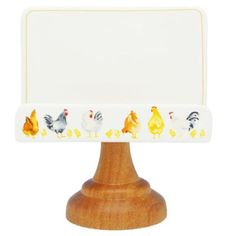 a wooden stand holding a white sign with chickens on it's front and sides