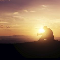 a person sitting on top of a hill at sunset