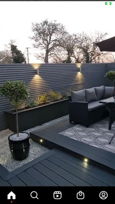 an outdoor living area with black furniture and lights on the side of the fenced in area