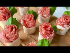 small appetizers are arranged on a cutting board with leaves and meat in them