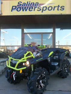 a large four - wheeler parked in front of a power sports store with its lights on