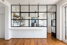 an empty room with wooden floors and glass walls on the wall, along with a white counter