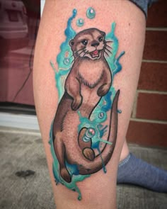 an otter tattoo on the leg of a person's leg, with bubbles coming out of it