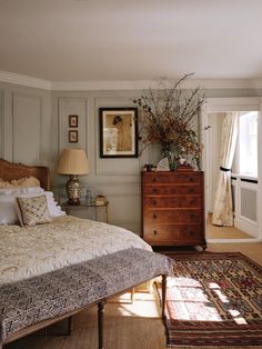 a bed sitting in a bedroom next to a dresser and lamp on top of a rug