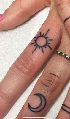 two fingers with sun and moon tattoos on them