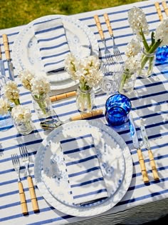 the table is set with blue and white plates, silverware, and flowers in vases