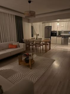 a living room filled with furniture next to a kitchen and dining table in front of a window