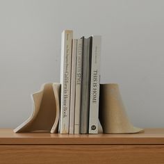 two books are stacked on top of each other in front of a white wall and wooden shelf