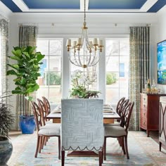 a dining room table with chairs and a chandelier hanging from it's ceiling