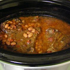 a slow cooker filled with meat and beans