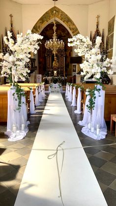 an aisle decorated with white flowers and greenery