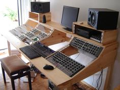 there is a computer desk with many keyboards and speakers on it in the living room