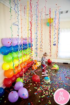 balloons and streamers are on the floor in front of a wall with confetti