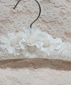 a bridal garter with flowers and pearls on it, hanging from a hook